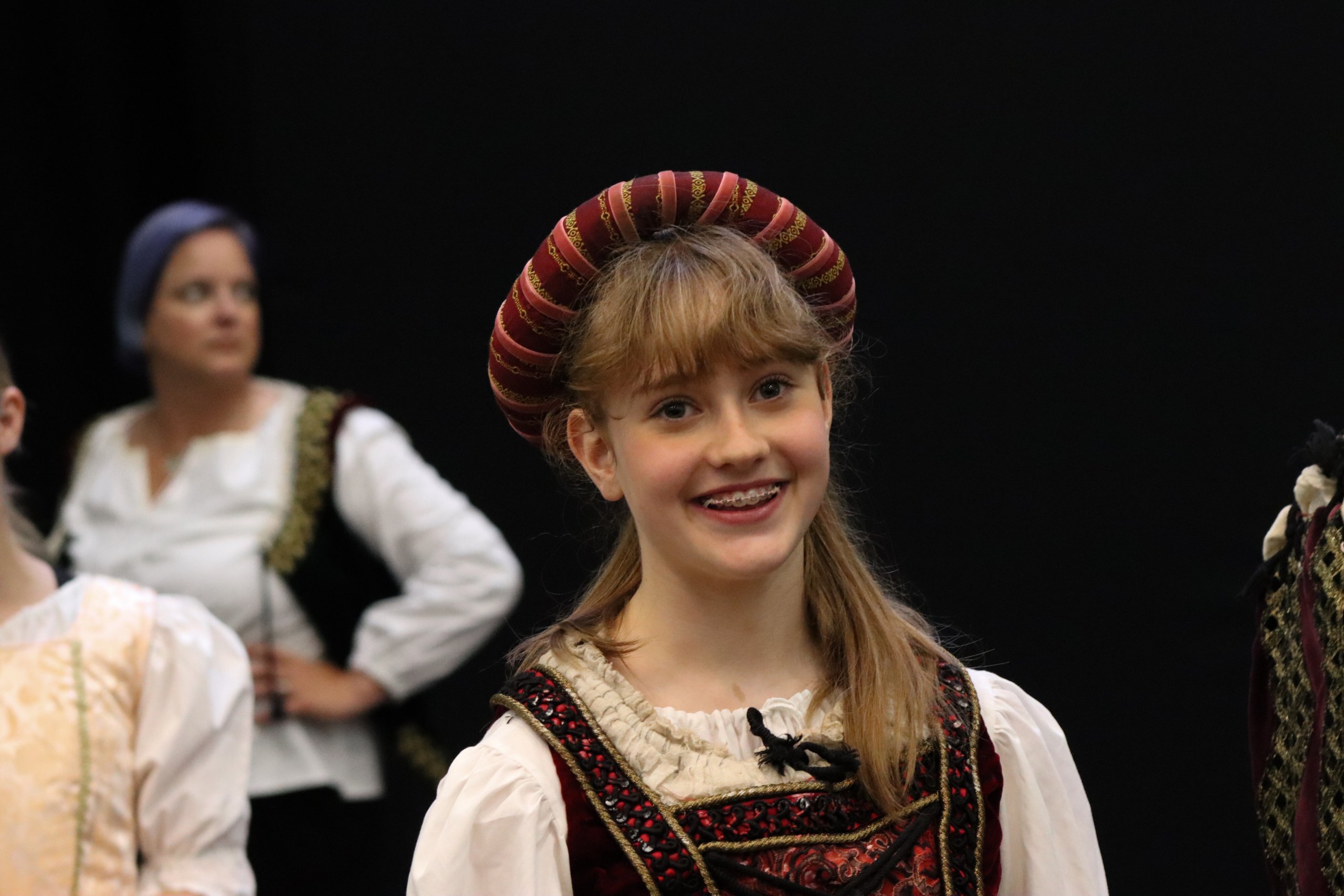 A dancer in costume smiling facing forwards. 
