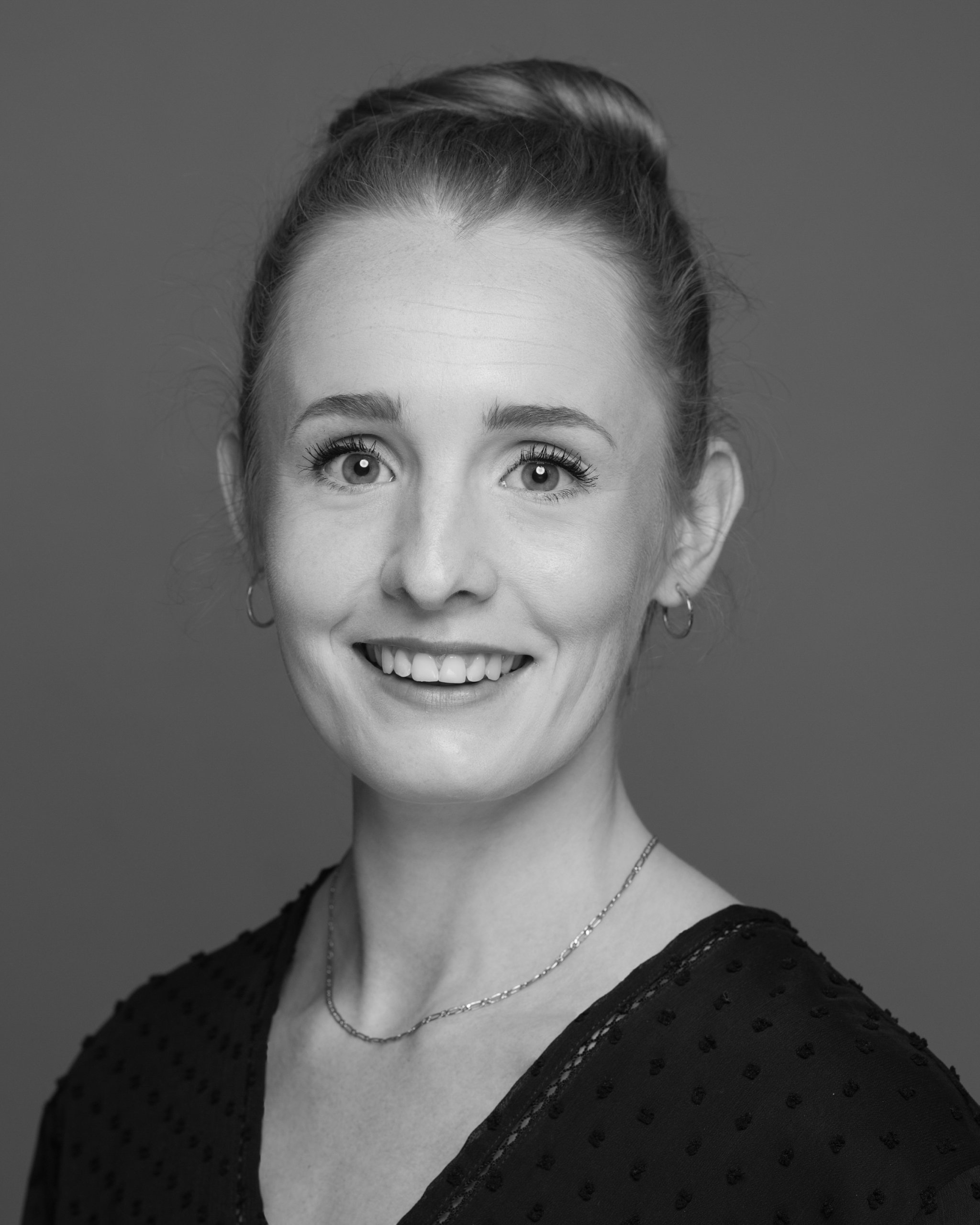 A black and white colourised headshot of Amelia O'Hara. Photographed by Tina Frances